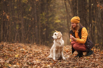 Young woman playing with golden retriever in autumn forest