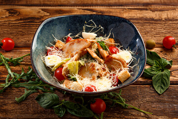 Caesar salad with chicken on a wooden background