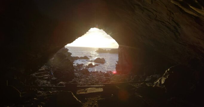 Woman hikes on rocky coastline on Easter Island at sunset, dolly shot