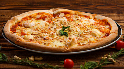 Pizza with garlic slices and spices on wooden background