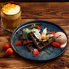 Chocolate waffles with strawberries and mint on wooden background