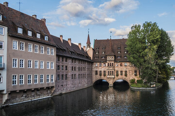 Fototapeta na wymiar Ancient Nurnberg Heilig Geist Spital building (Hospital of the Holy Ghost, 1339) over Pegnitz river. View from the Bridge on the River Pegnitz. Nuremberg, Germany.