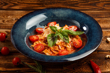 pasta with cherry tomatoes and basil on wooden background