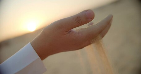 Close up, man picks up desert sand in Saudi Arabia