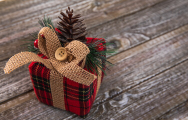 petit cadeau rouge et vert avec ruban déposé à gauche sur une surface en bois foncé