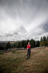 portrait of a young pretty girl who stands alone against a 
background of mountains. beautiful sky, beautiful nature