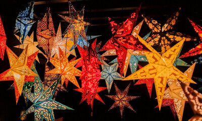 many colorful stars for the Christmas tree that glow on a black background