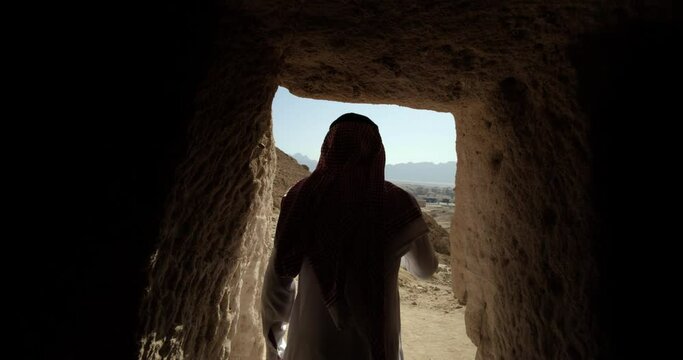 Saudi Arabia man exits temple in desert, tracking shot