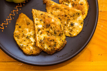 Vegetarian food - celery tuber slices fried in batter in a ceramic plate on a wooden table, close up