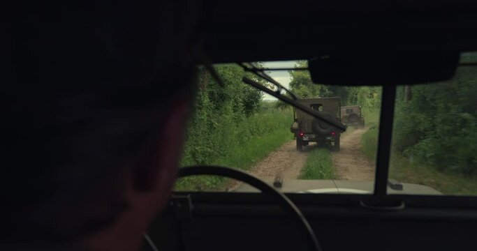 Close up, soldier drives military jeep down dirt road in French countryside