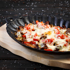baked meat with cheese and tomatoes on a wooden background
