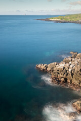 Scenic view, seen using a long exposure, of the Pacific ocean from Las Tijeretas outlook. Kicker Rock can be seen on the horizon on a very sunny afternoon. San Cristobal island, Galapagos Islands.