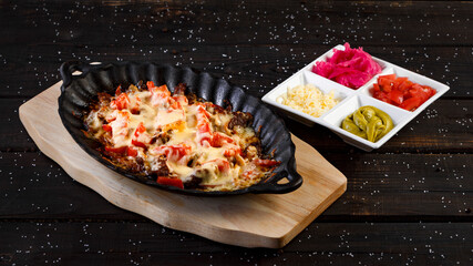 baked meat with cheese and tomatoes on a wooden background
