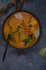 Obraz na płótnie Canvas Vegan thai red curry with carrot, tofu and bock choy in black bowl, copy space