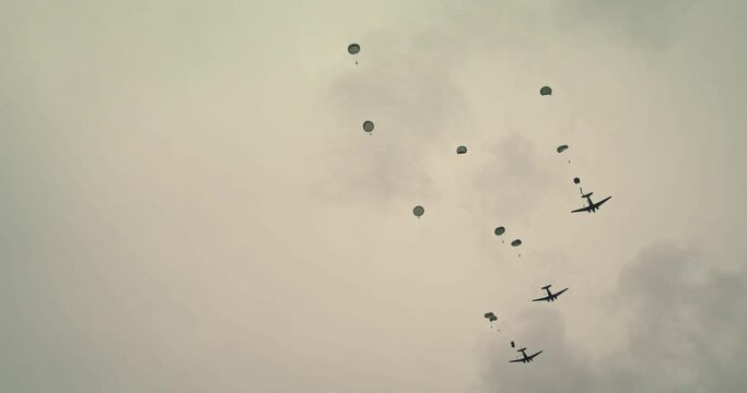 Low angle, parachuting soldiers on overcast day