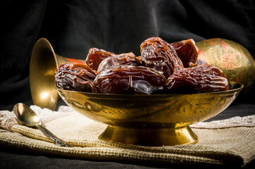 Big luxury dried date fruit in bowls on a linen napkin, kurma ramadan kareem concept, close up.