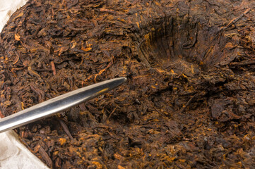 Chinese pressed PU-erh tea on wrapping paper and tea knife, close-up, macro