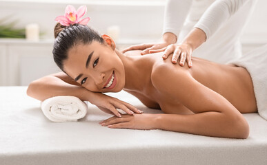 Obraz na płótnie Canvas Wellness Concept. Beautiful asian lady enjoying back massage in spa center