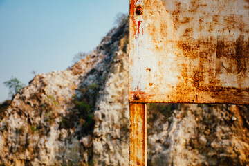Old rusty blank metal sign in front limestone mountains background in Thailand. Limestone mountain texture.
