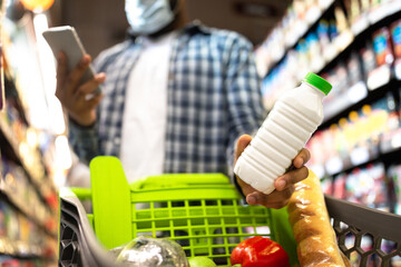 Fototapeta na wymiar Black Man In Mask Using Smartphone Buying Food In Supermarket