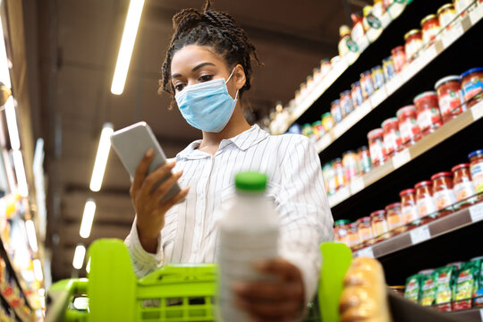 Black Lady In Mask Using Phone Shopping In Grocery Shop