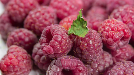 Ripe juicy raspberries lies on a plate. Ripe organic raspberries close-up.