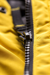 Zipper on clothes close-up. black color. Bright yellow jacket