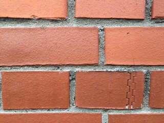 One brick in the wall with a small defect. Brick wall, brown brick with gray mortar between them. there is a flaw on one of the bricks.