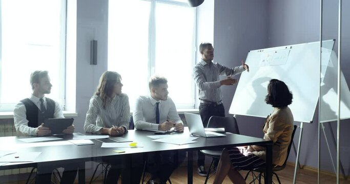 Male executive african leader presenter giving lecture presentation in modern office boardroom for corporate employees multiracial multiethnic group, speaker mentor training team at business seminar