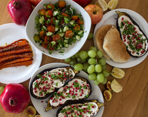 Grilled eggplants, salad, caramelized carrots and fresh fruits on wooden table. Top view photo of different vegetarian meals. 