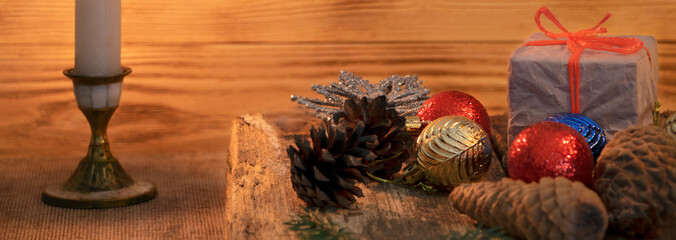 Christmas gifts on a wooden background. Fir branch and cones. Blur background. Banner. Candle