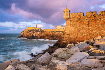 Fototapeta na wymiar Peniche Fortress at sunset with beautiful golden light with sea waves crashing on the rocks, in Portugal