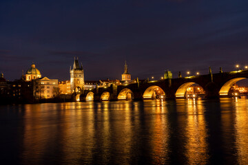 Obraz premium illuminated stone monument of Charles Bridge from the 14th century on the Vltava river and lights from street lighting in the center of Prague