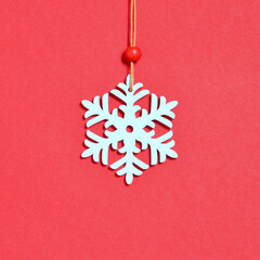 Wooden Christmas snowflake decoration on red background. Minimalistic Christmas concept