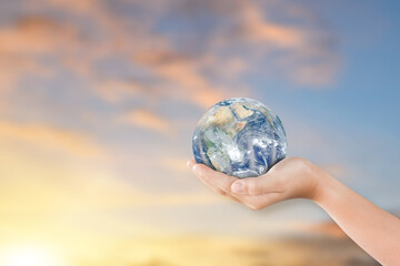 Concept of world environment day: Hand holding earth globe over blurred nature sky background. Elements of this image furnished by NASA