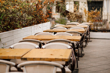Empty tables and chairs in a cafe on the street. Indoor restaurant in autumn. selective focus