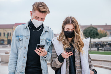 Couple wearing face masks and using their smartphones