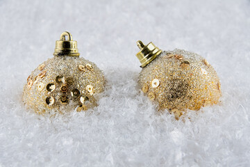 Gold Christmas baubles on snow