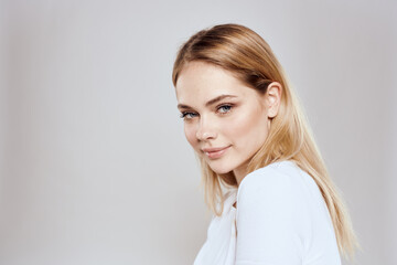 Cheerful blonde woman in white t-shirt cropped view light background