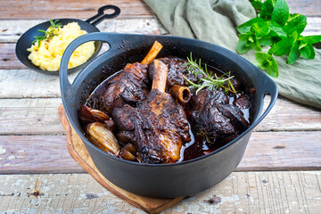 Modern style traditional braised slow cooked lamb shank in red wine sauce with shallots and mashed...
