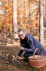 Girl with glasses in the autumn forest. Woman with a a basket walks in the woods. Autumn walk.