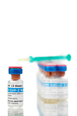 Bottles of new SARS-CoV-2 vaccine on table with plastic syringe