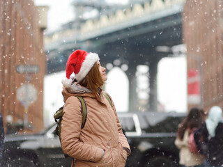 A young woman tourist in a Santa Claus hat walks during a snowfall in New York City on Christmas...