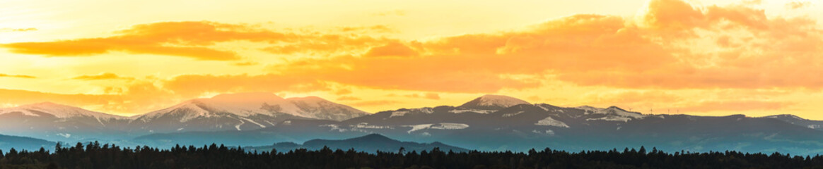 Styrian Lavanttaler Alps covered with snow in orange light of sunset.