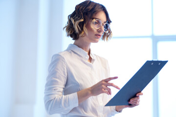 Business woman in the office with documents in the hands of the window in the background finance work