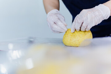 Woman hands preparing bread dough on kitchen table.