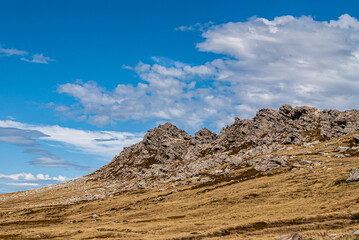 Falkland Islands, UK - December 15, 2008: Wide windswept bare landscape of dry land with gray sharp rocky outcrop under blue cloudscape.