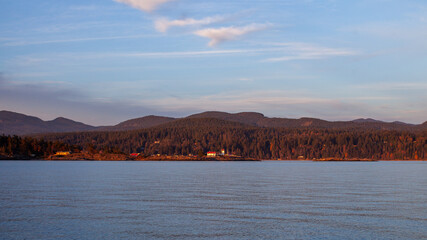 A view of Merry Island Lighthouse, along the Sunshine Coast at sunset, on the Pacific Ocean in British-Columbia. The lighthouse marks the entrance of Welcome Pass