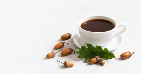 Obraz na płótnie Canvas Small cup of black coffee, oak leaf and acorns on a white background. Acorn coffee without caffeine. Autumn still life. Copy space.
