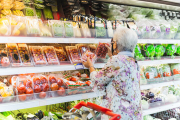 Woman wearing protective mask doing grocery shopping in supermarket.
